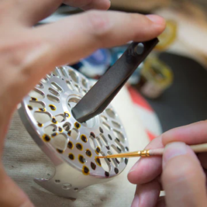 Ein Fish Skin Finish wird in Handarbeit vor dem anodisieren auf der Abel Fliegenrolle aufgemalt